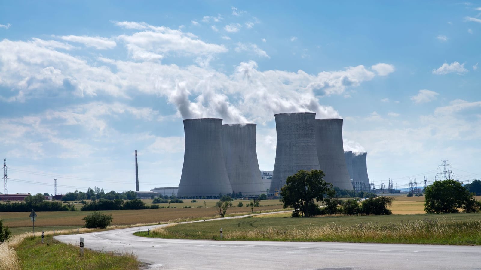 Cooling towers of Dukovany Nuclear Power Plant on a sunny day with smoke rising.