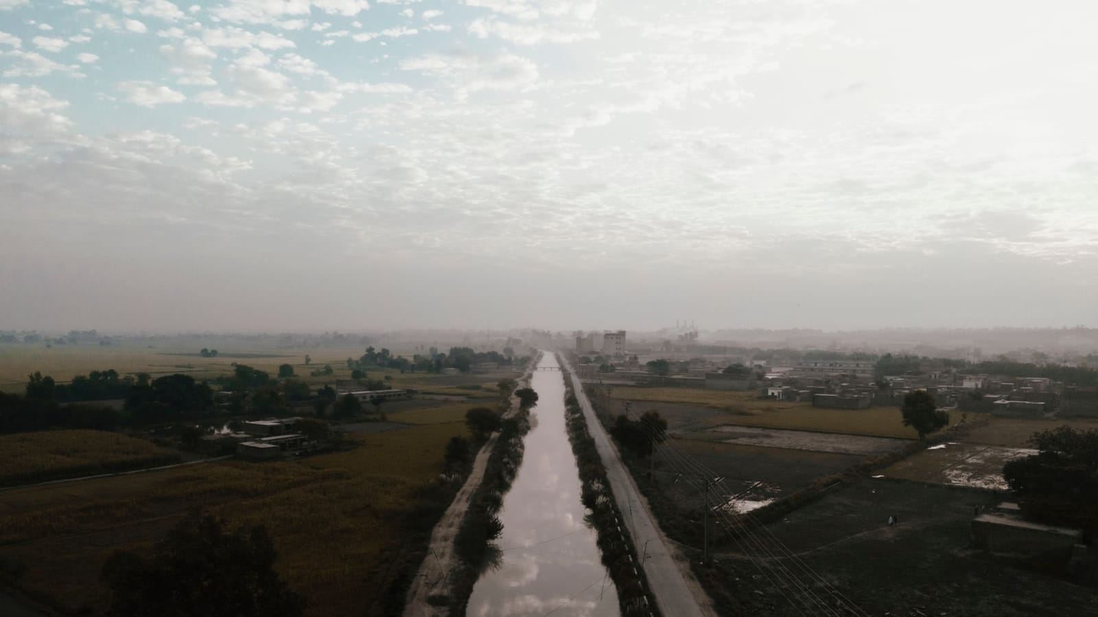 Aerial view of farmland with a canal in Gujranwala, Punjab, Pakistan on a cloudy day.