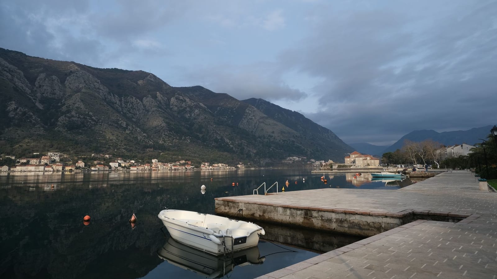 Peaceful morning view of Kotor Bay in Montenegro, showcasing calm waters and mountainous backdrop.