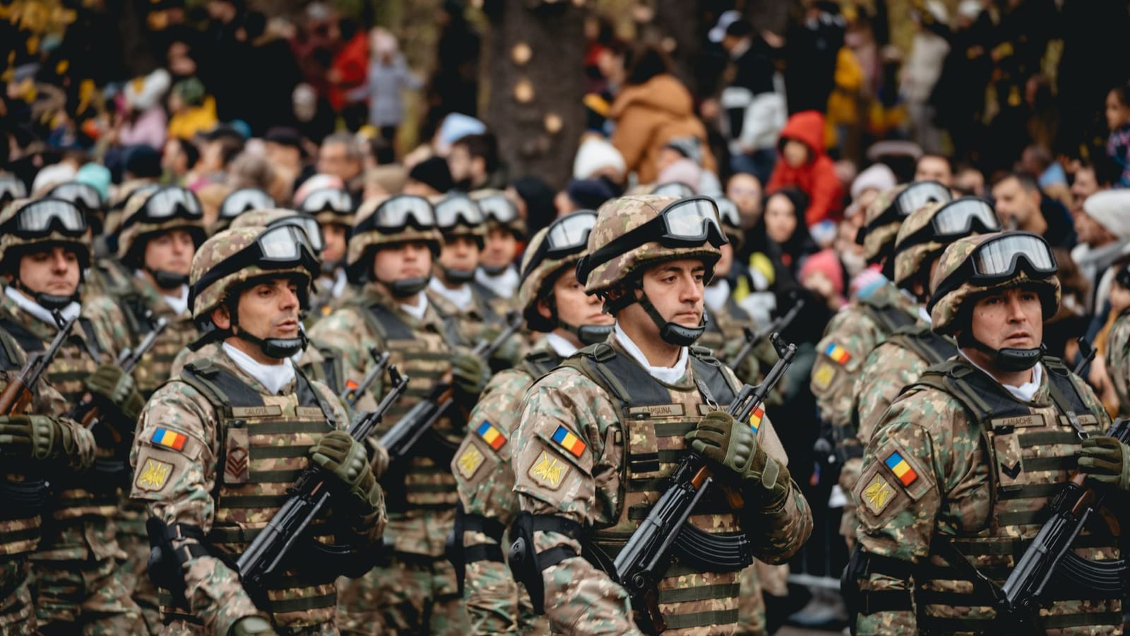 Soldiers in uniform march during a military parade featuring diverse troops and spectators.