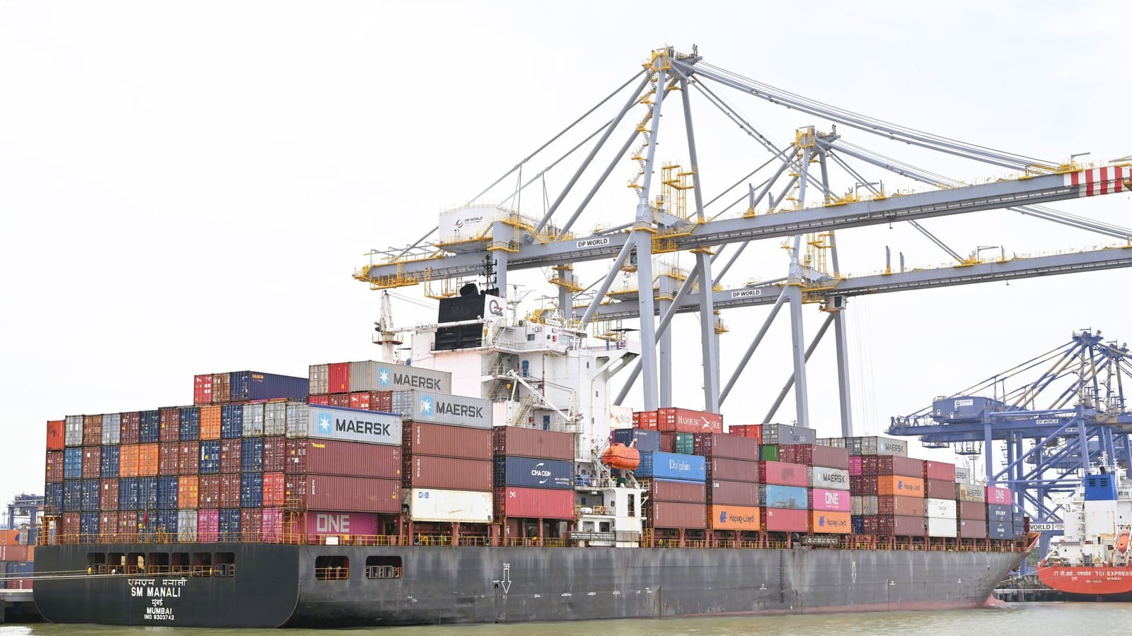 Cargo vessel moored at Kochi, Kerala, India, showcasing global container shipping with cranes in background.