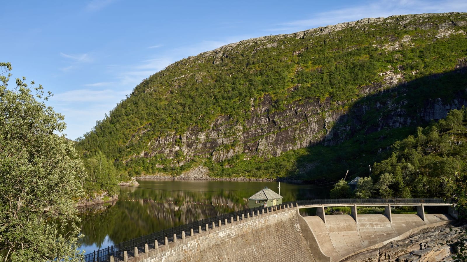 A picturesque view of a water dam nestled in a mountainous landscape reflecting calm waters.