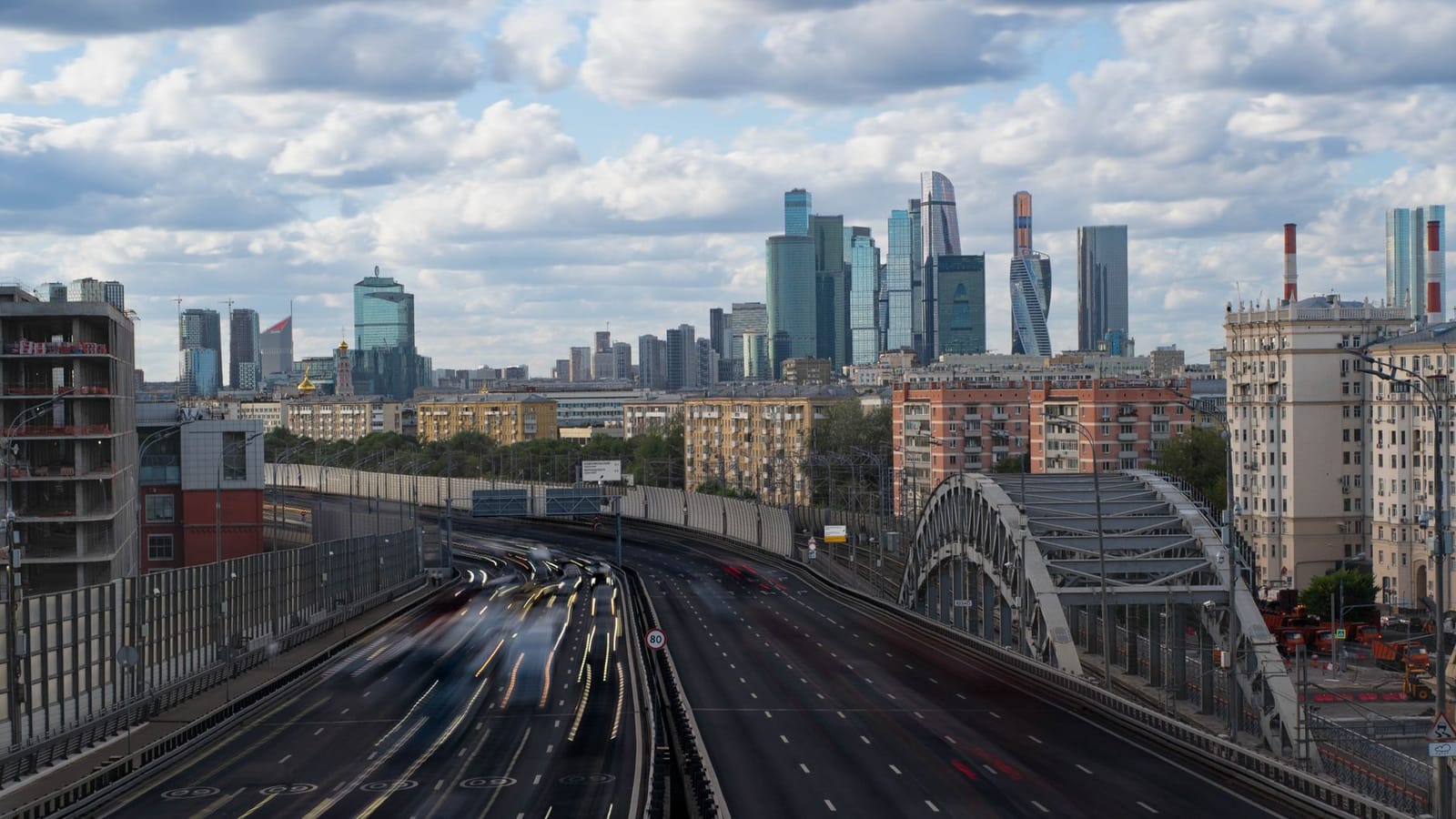 A view of Moscow's skyline featuring modern skyscrapers and a busy highway under a cloudy sky.