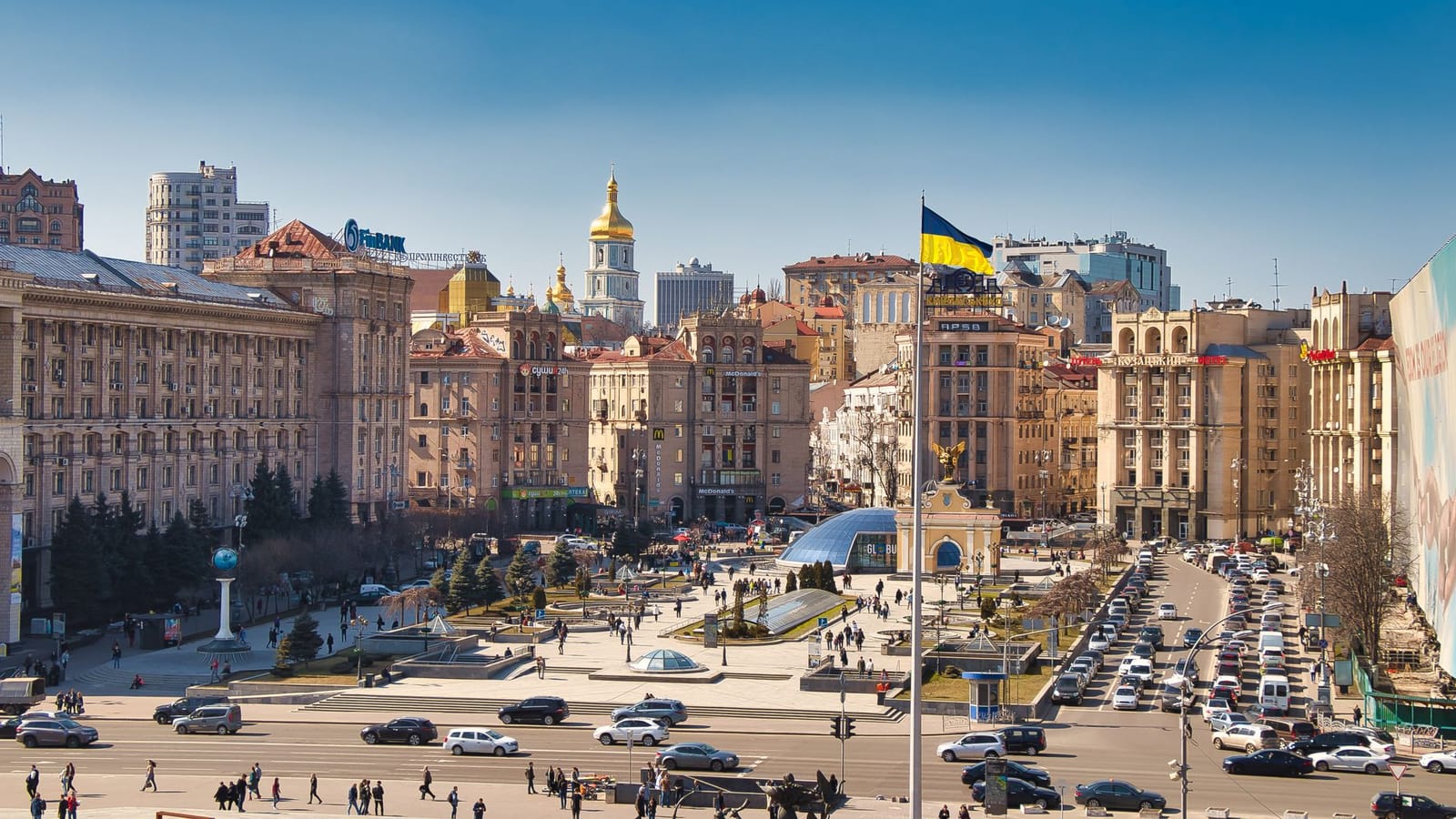 A bustling daytime scene at Independence Square in Kyiv, Ukraine, showcasing historical architecture and city life.