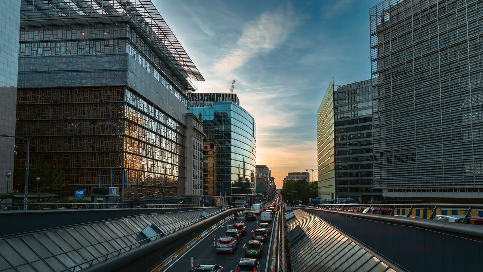 Busy Brussels street lined with modern office buildings during sunset, showcasing urban life.