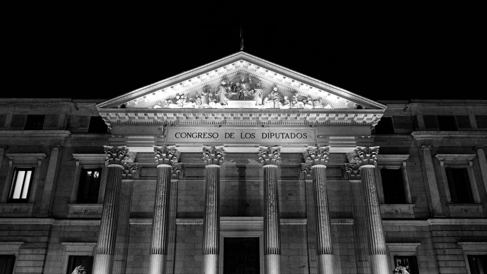 Black and white photo of the Congress of Deputies facade in Madrid by night.