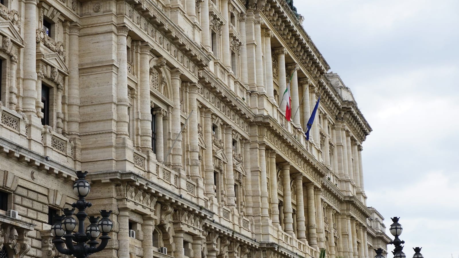 A captivating view of a neoclassical building facade in Rome with Italian flags and detailed architecture.