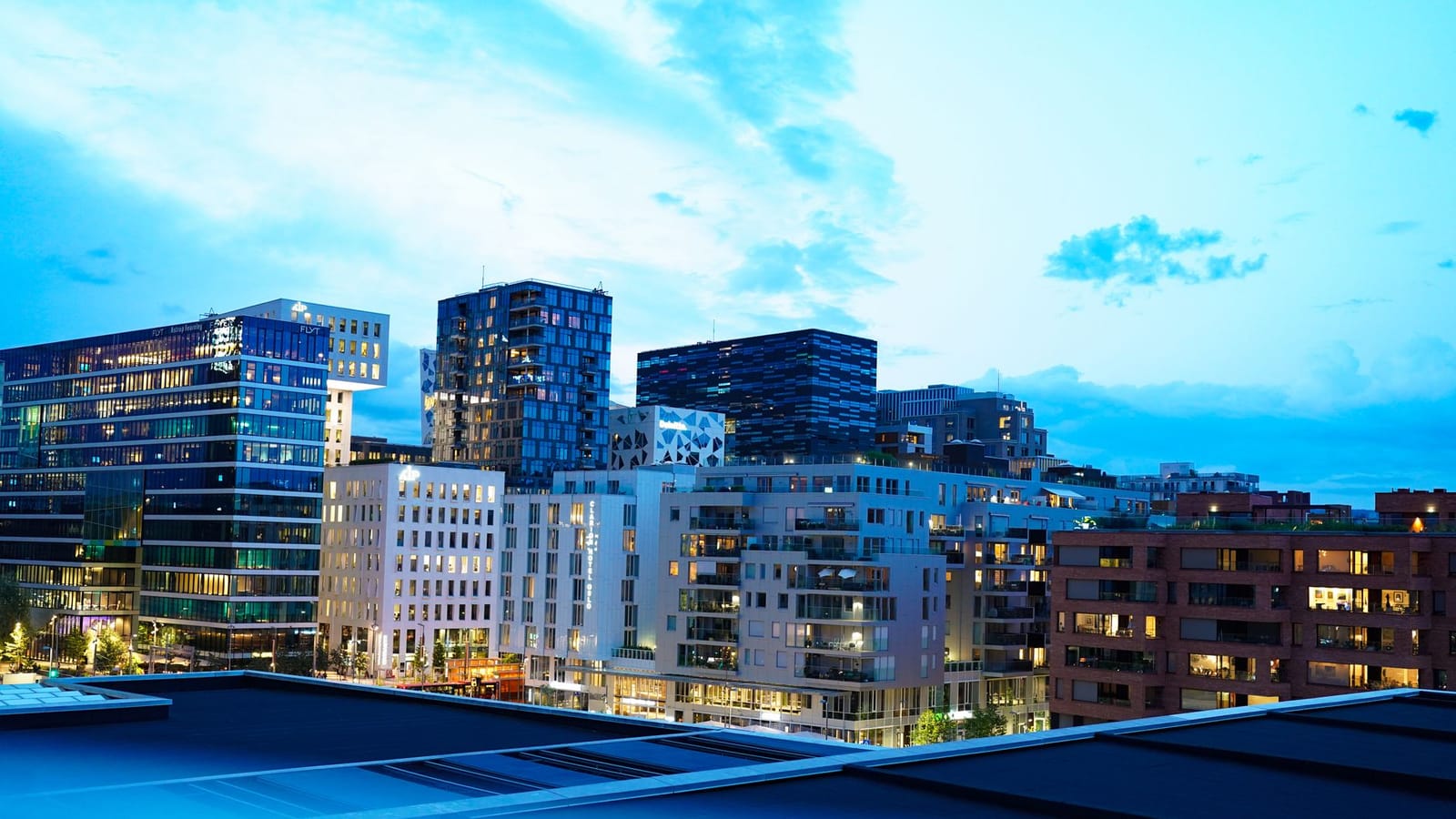 Illuminated modern buildings in Oslo's downtown at twilight, showcasing architecture.