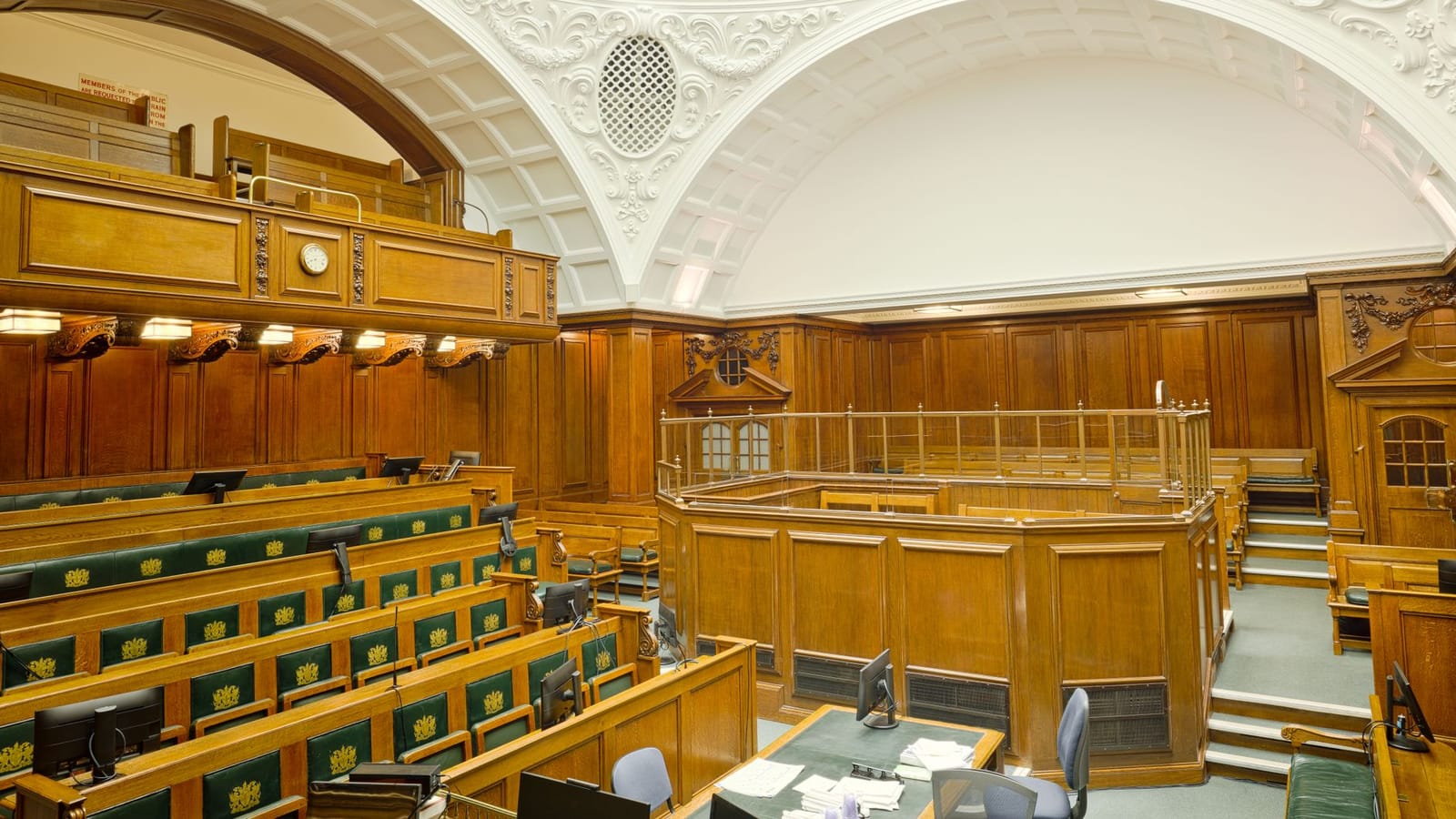 Interior view of a historic courtroom in London with ornate design and wooden furnishing.