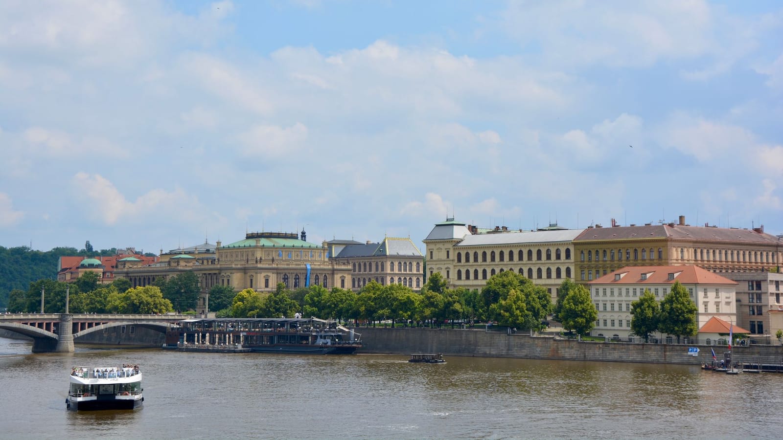 A picturesque view of Prague with the Vltava River, historical buildings, and a bridge.