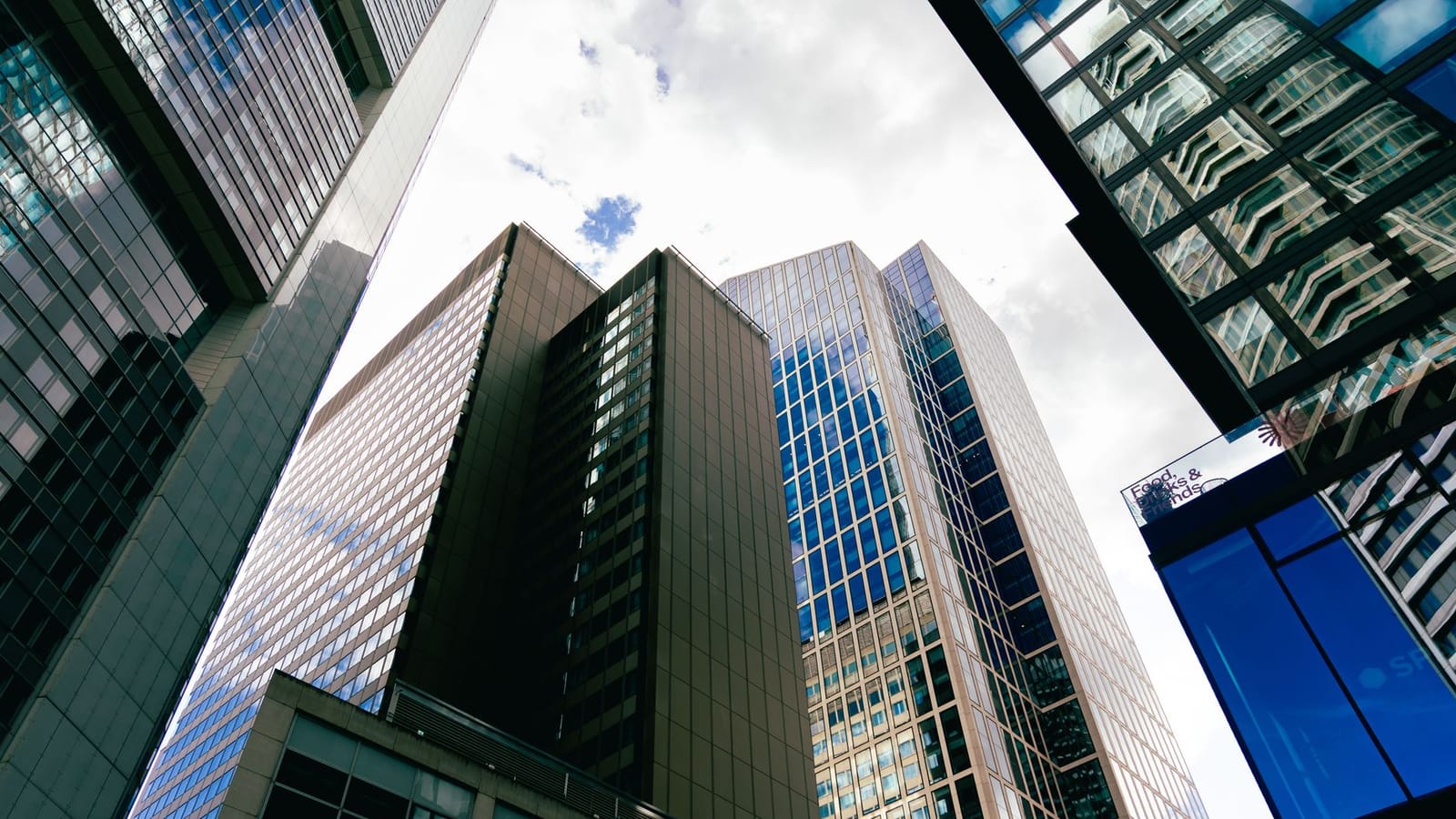Tall skyscrapers in downtown Frankfurt am Main with a cloudy sky backdrop, showcasing modern architecture.