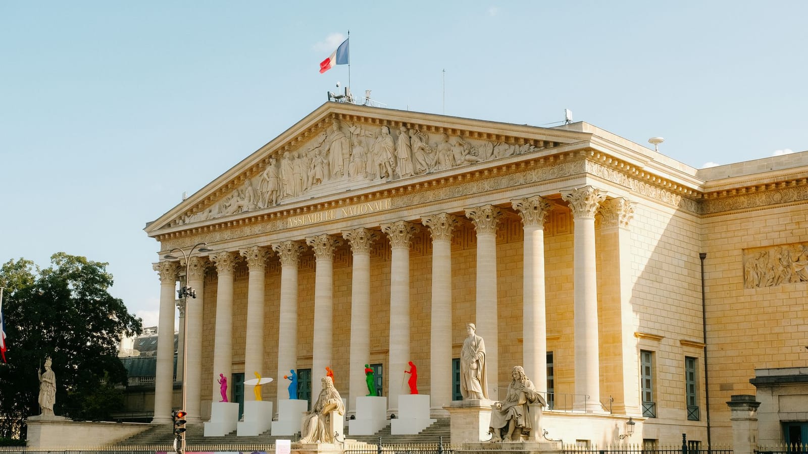 Front view of the Palais Bourbon in Paris, featuring statues and French flag.
