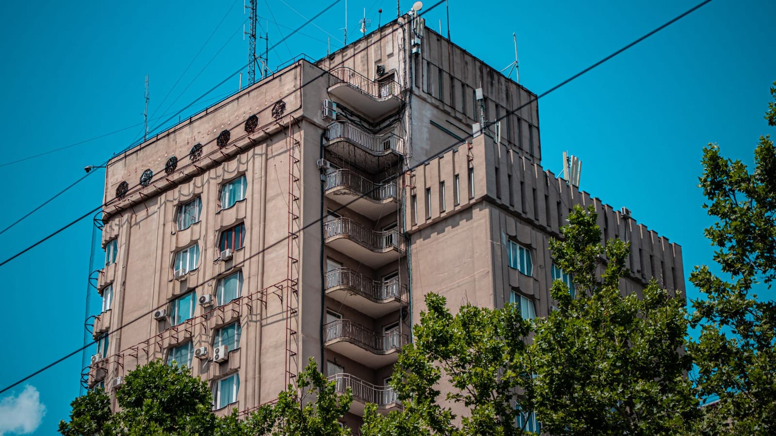 Elevated view of a residential building in Chișinău, Moldova with clear blue sky and surrounding greenery.