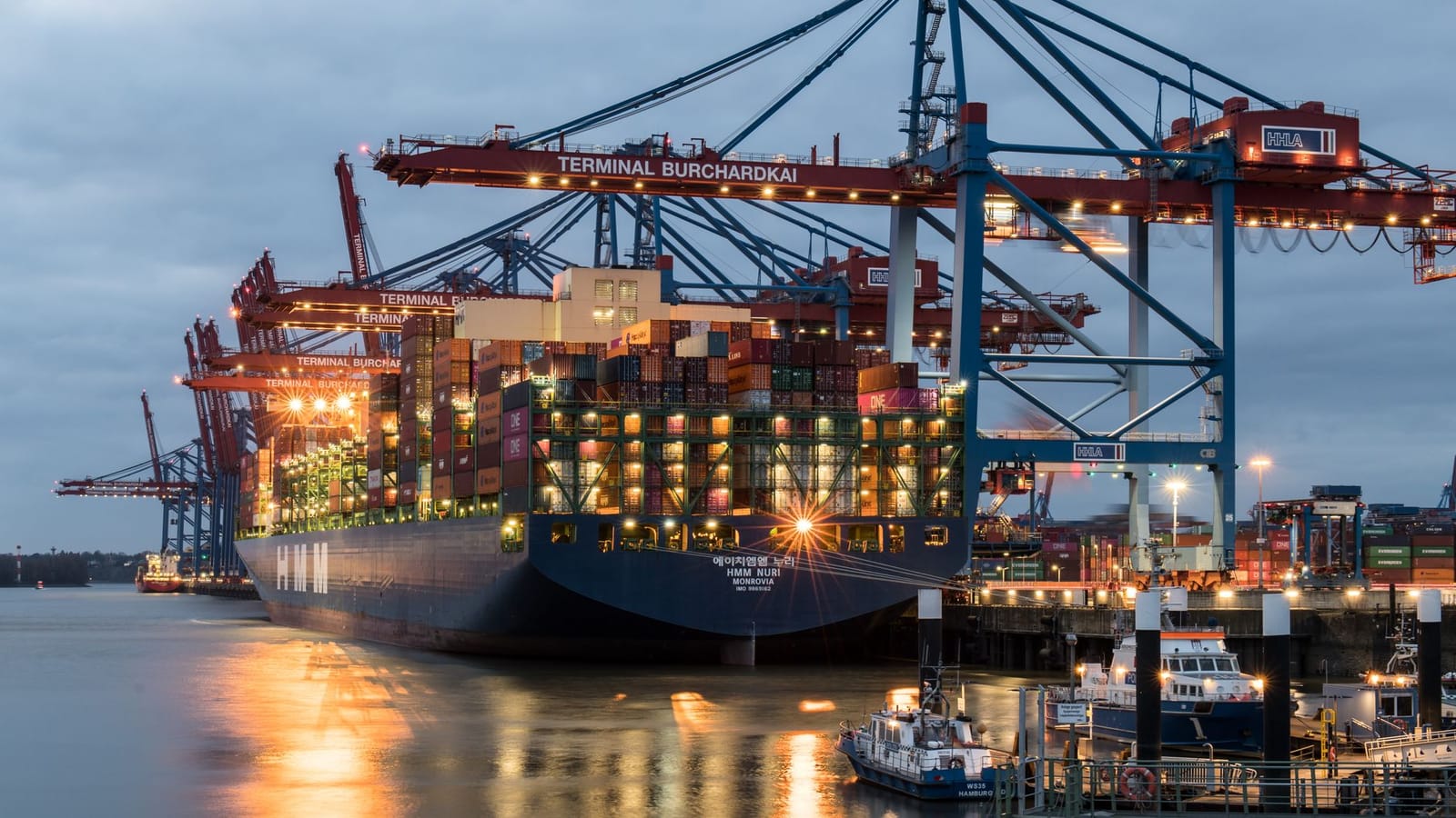 Container ships moored at Terminal Burchardkai in Hamburg, Germany during evening hours.