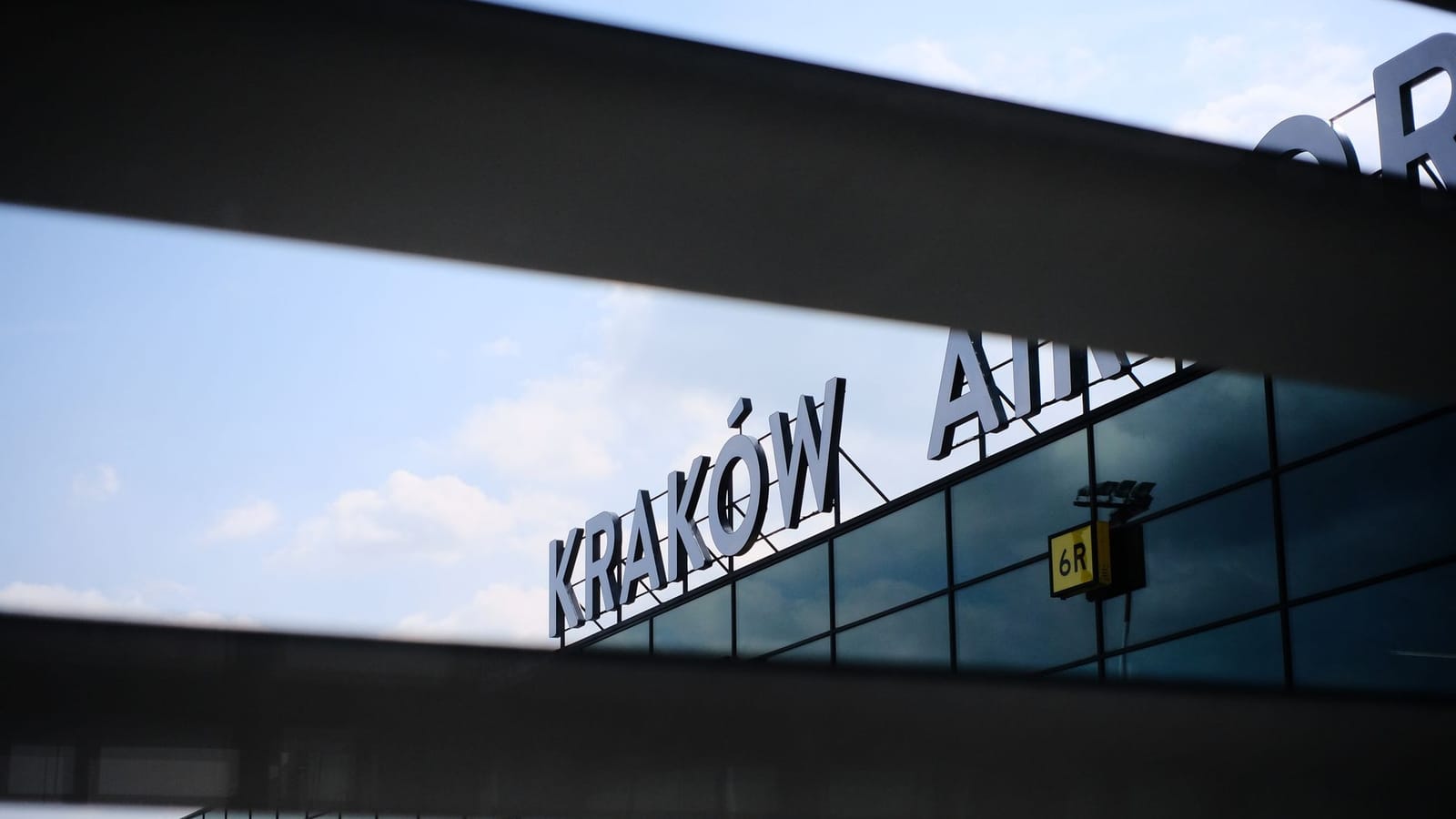 A modern architectural detail of the facade of Kraków Airport with reflective glass panels.