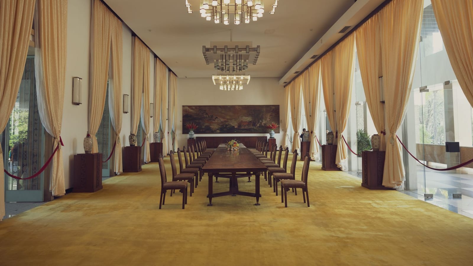 Spacious banquet room with luxury decor in Reunification Palace, featuring elegant chandeliers and long dining table.