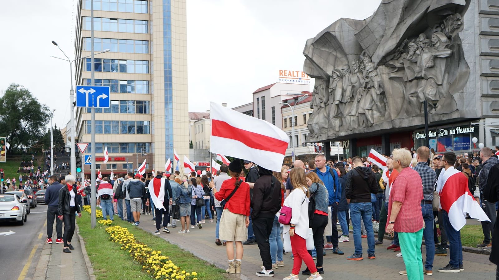 Crowd gathers for a protest in central Minsk, Belarus, holding flags and demonstrating peacefully.
