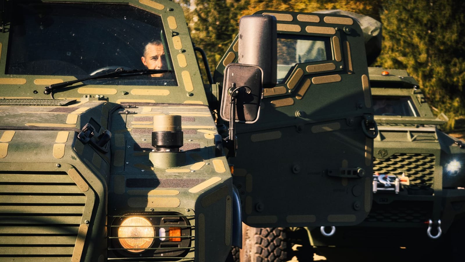 Armored military vehicle with camouflage and driver, ready for action.