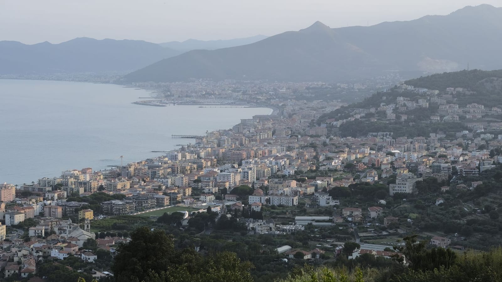 A breathtaking view of a coastal city in Italy with mountains and sea in the background.