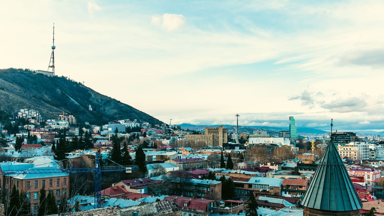 Aerial view of Tbilisi showcasing iconic landmarks and vibrant cityscape under a clear sky.