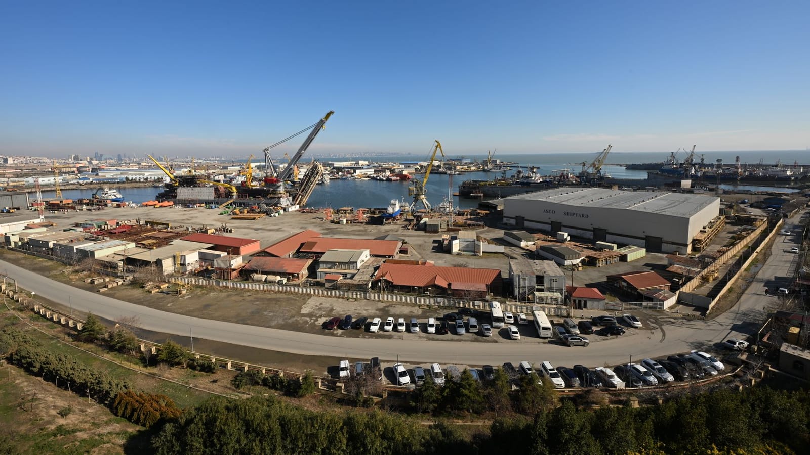 Aerial view of Baku's bustling harbor and shipyard under clear blue skies.