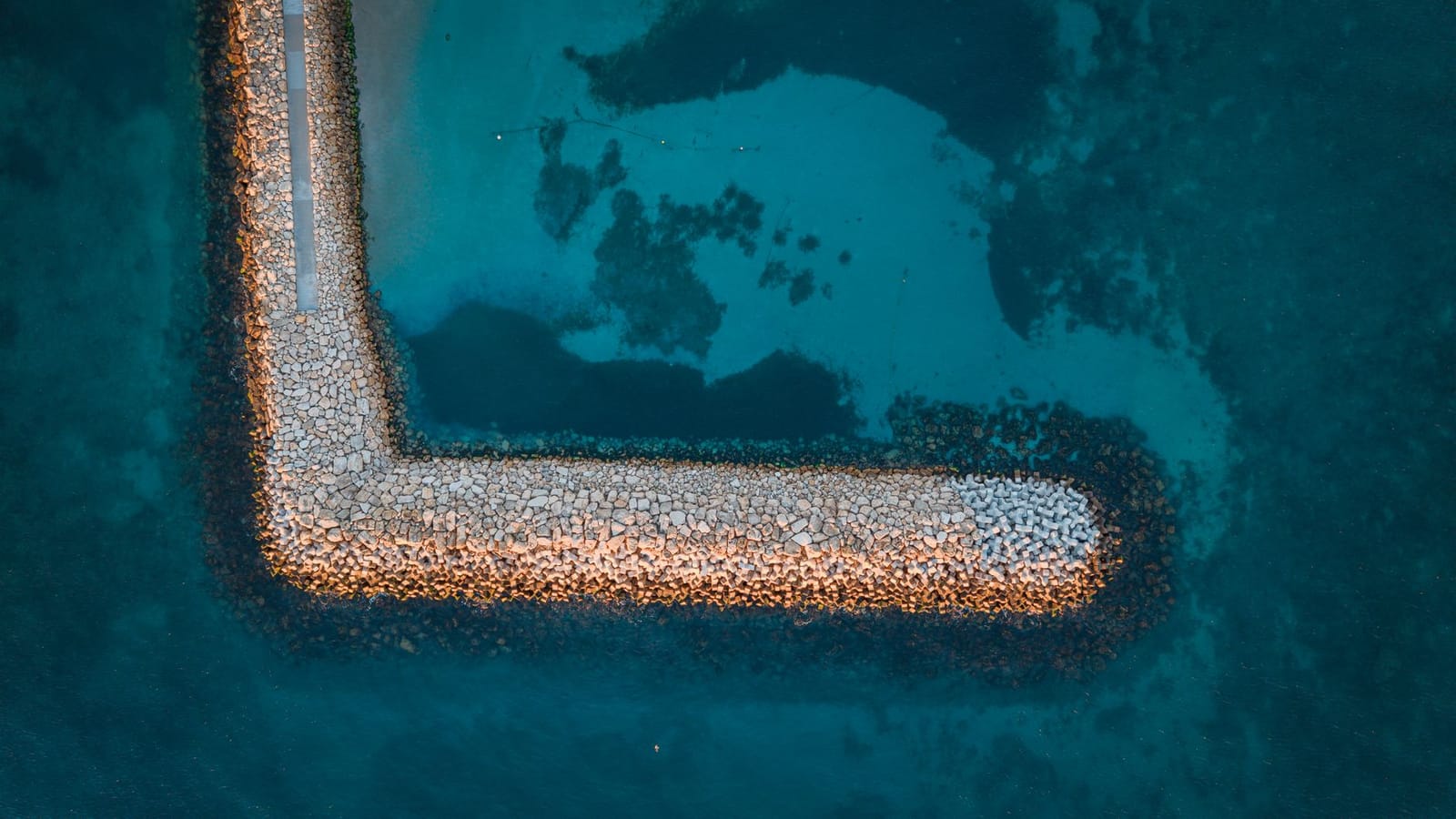Top-down view of a rocky breakwater along the coast of Constanța, Romania, against turquoise sea waters.