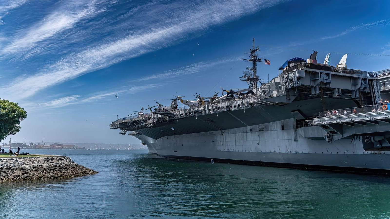 USS Midway Museum ship docked in San Diego harbor on a clear day, showcasing naval history.