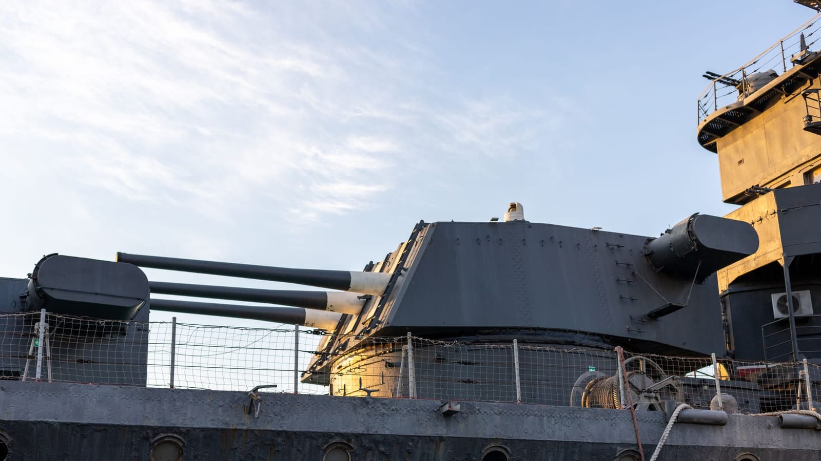 A detailed view of naval ship artillery under the evening sky, highlighting its structure and design.