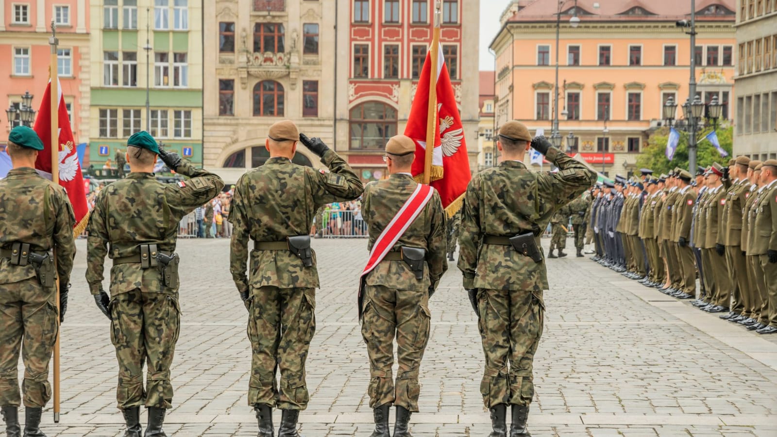 Polish soldiers saluting during a military parade in Wrocław city square, showcasing national pride.