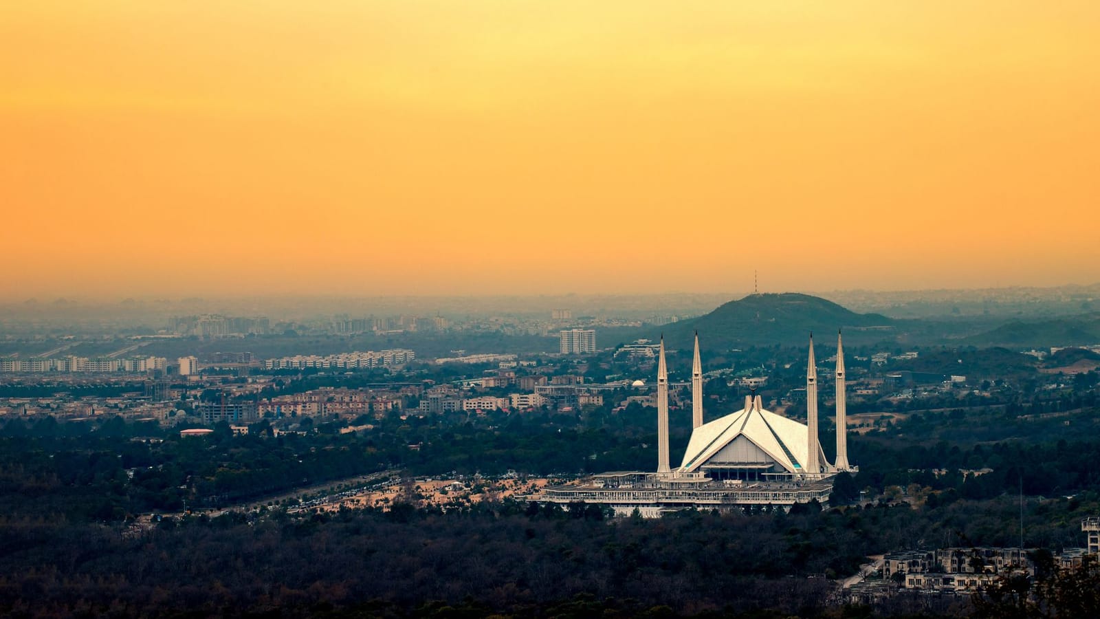 Captured from above, Islamabad's Faisal Mosque silhouetted against a vibrant sunset sky.