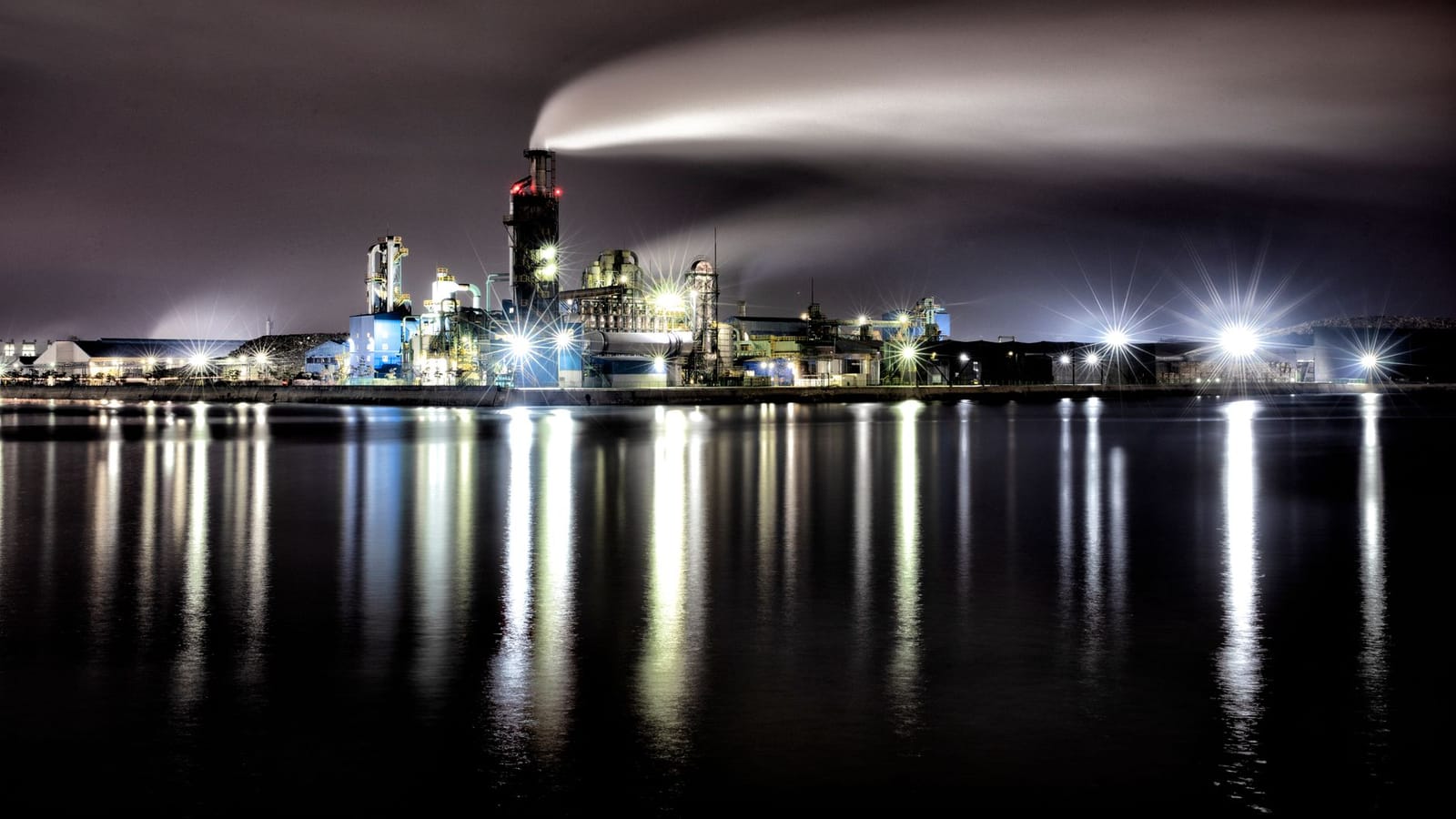 A night view of an illuminated industrial complex in Incheon, South Korea, reflecting vividly on tranquil waters.