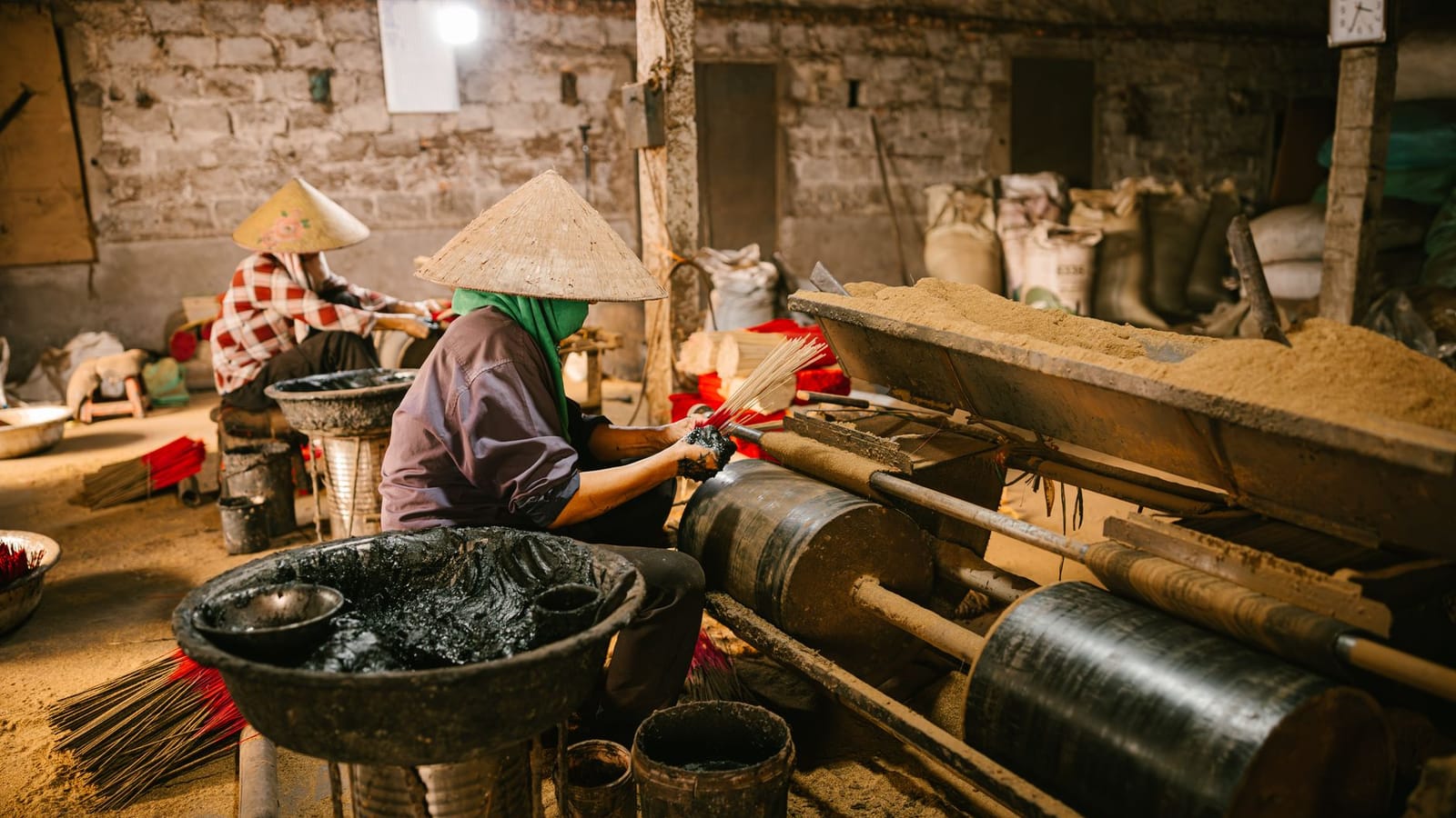 Workers creating incense sticks in a traditional workshop setting, showcasing cultural craftsmanship.