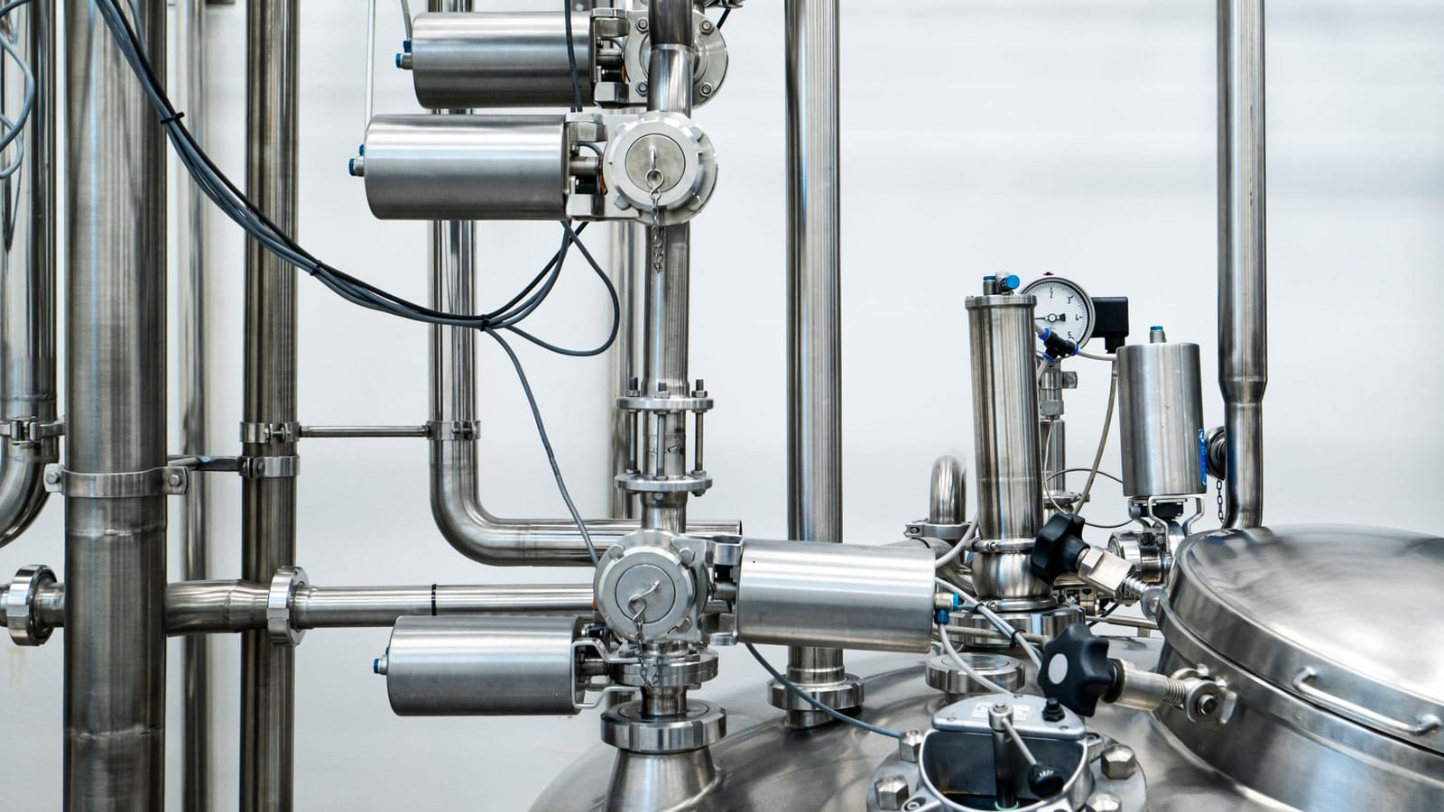 Close-up of stainless steel machinery and pipes in an industrial setting, showcasing modern engineering.