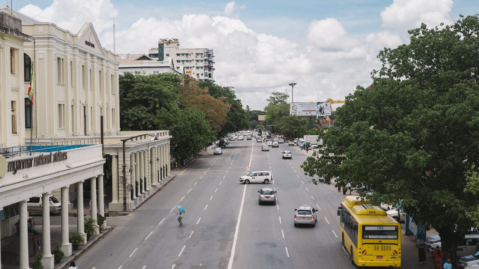 High angle view of a bustling street in Yangon with traffic and colonial architecture under a clear sky.