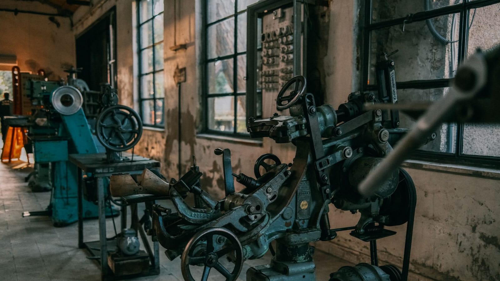 Old industrial machines in an abandoned workshop with vintage tools and equipment.