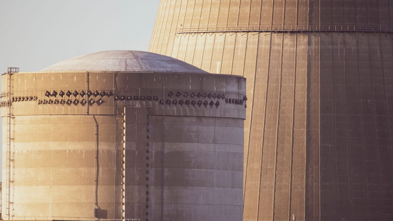 Close-up view of nuclear reactor buildings bathed in golden light, showcasing industrial architecture.