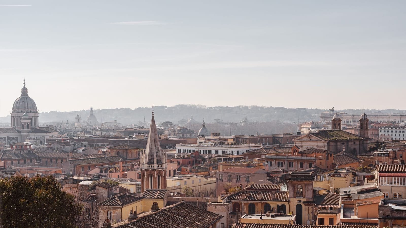 Cityscape with church and aged residential building facades with ribbed roofs under cloudy sky on sunny day