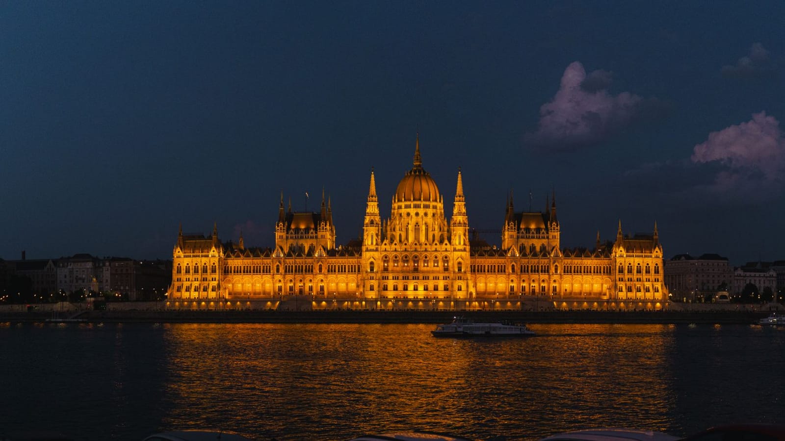 Night view of the glowing Hungarian Parliament Building reflected in the Danube River.