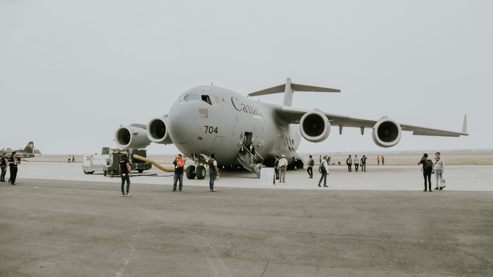 A C-17 Globemaster military aircraft is stationed on an airfield with crew members and personnel nearby.