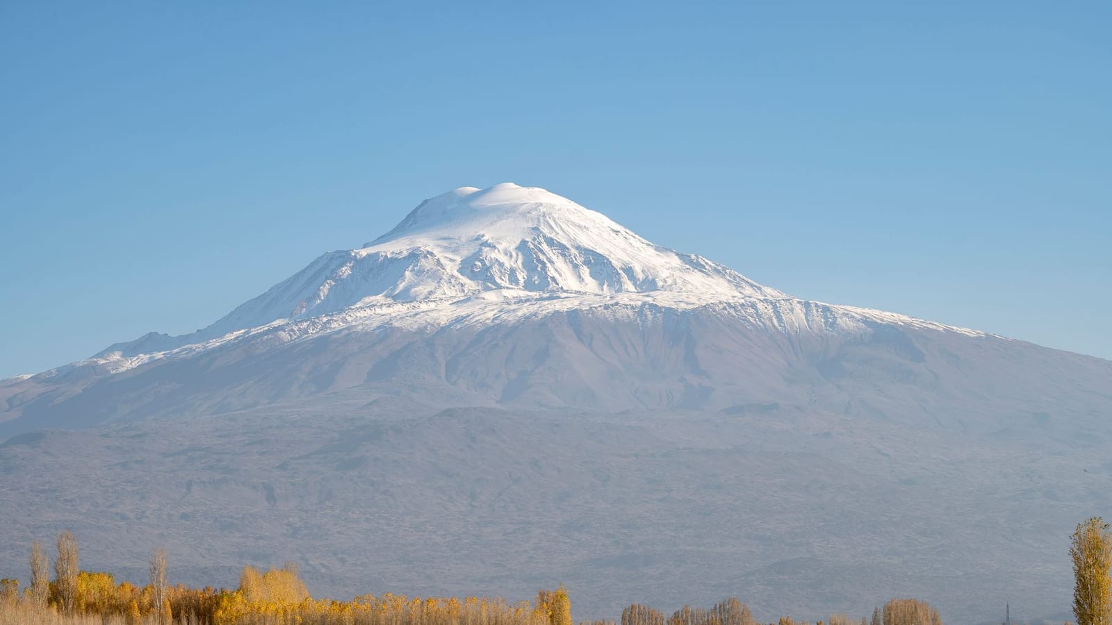 A stunning view of snow-capped Mount Ararat in Turkey surrounded by autumn foliage and clear skies.