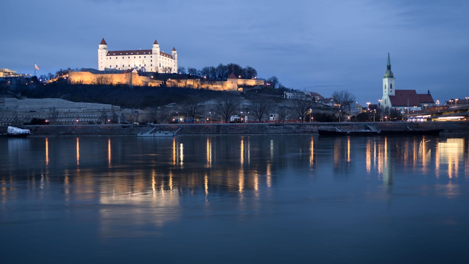 A captivating nighttime view of Bratislava Castle reflected in the Danube River.