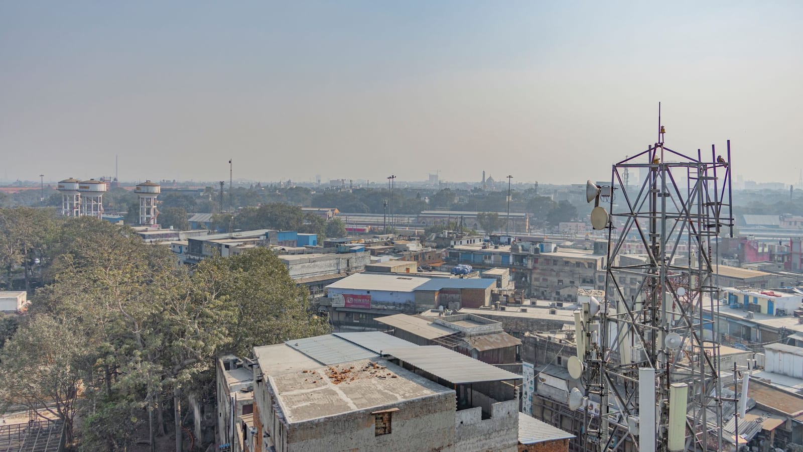 Aerial view of urban buildings and trees with a telecom tower in New Delhi, India.