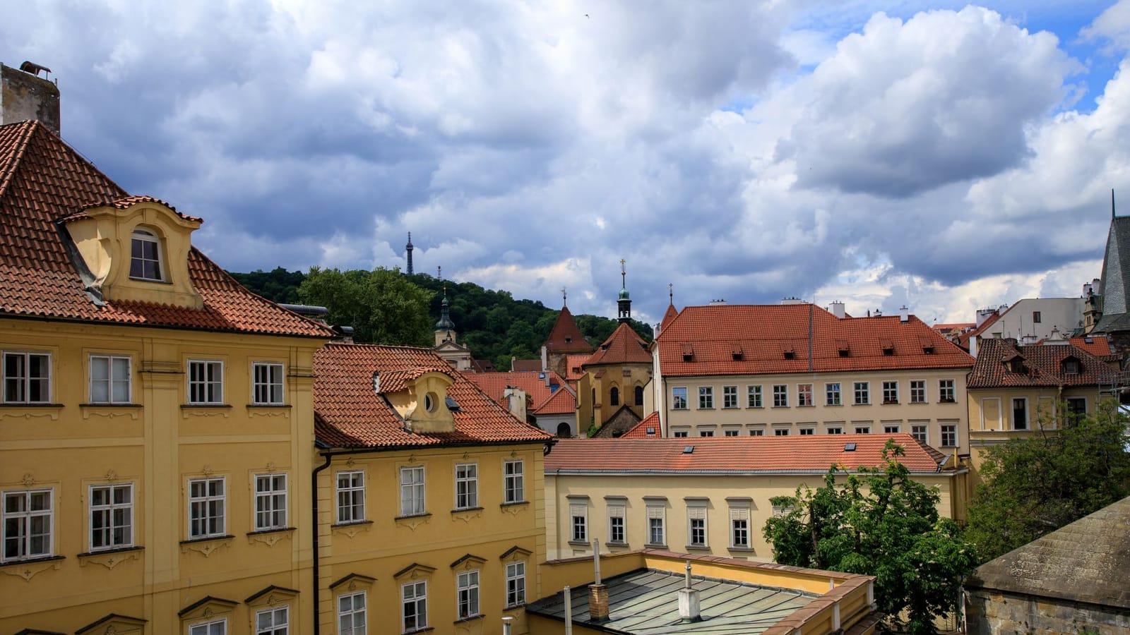 Charming view of Prague's historical buildings with red rooftops and cloudy sky.