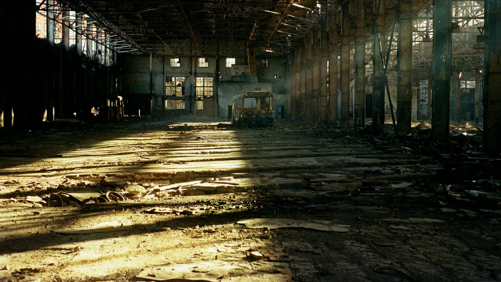 Sunlit interior of an abandoned warehouse, showcasing decay and atmospheric lighting.