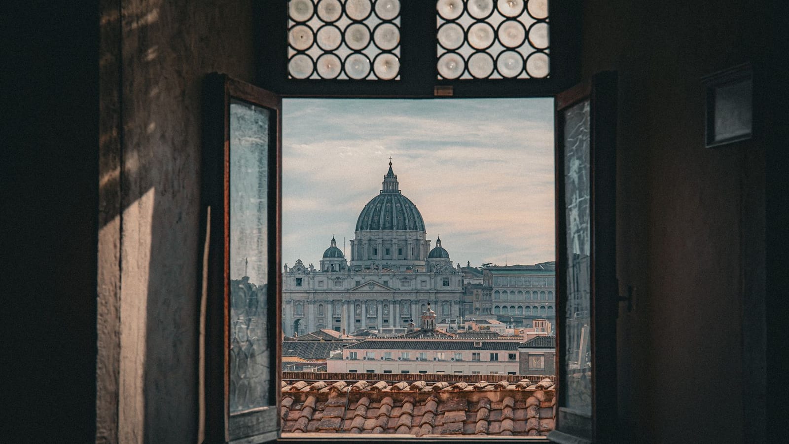 View of St. Peter's Basilica from an open window in Rome, Italy, capturing its iconic architecture.