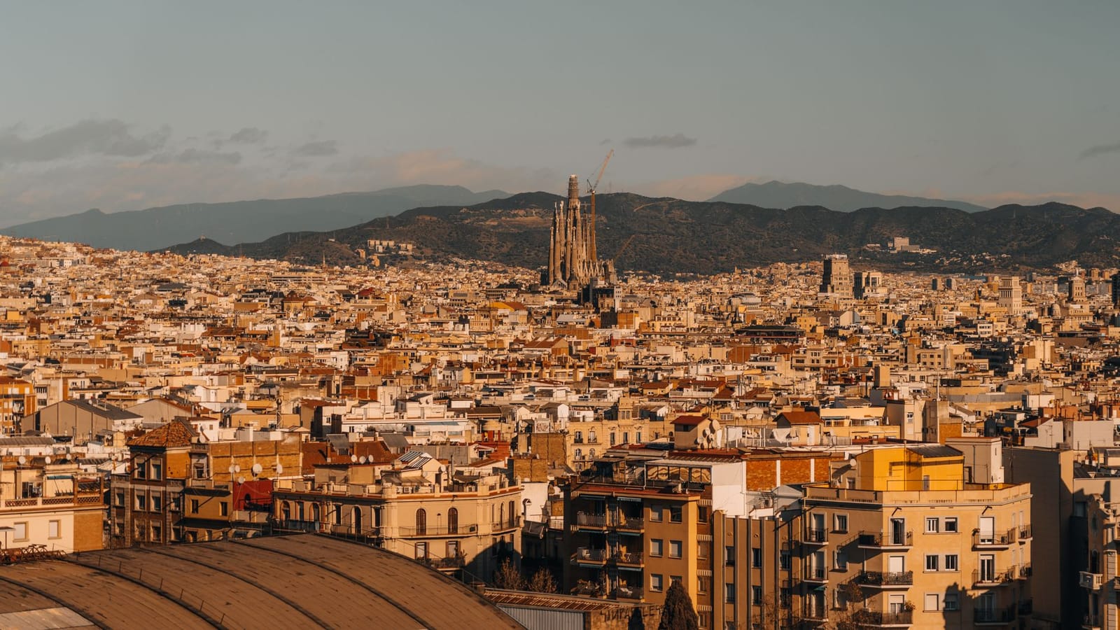Aerial view of Barcelona with the iconic Sagrada Familia under a clear sky.