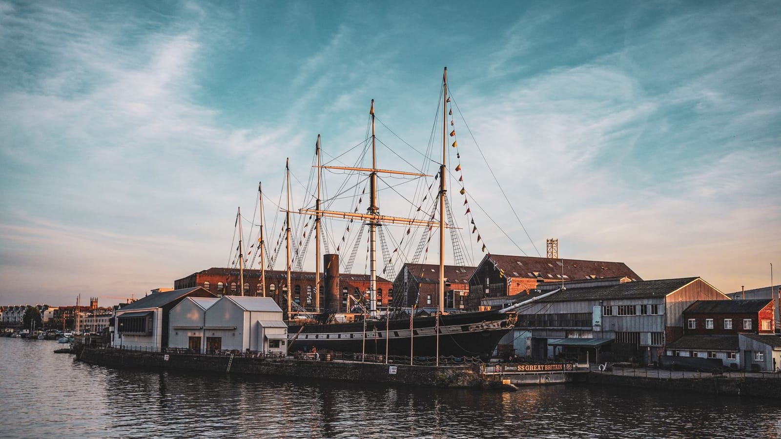 A majestic ship in a bustling urban harbor at sunset, reflecting the beauty and history of maritime heritage.