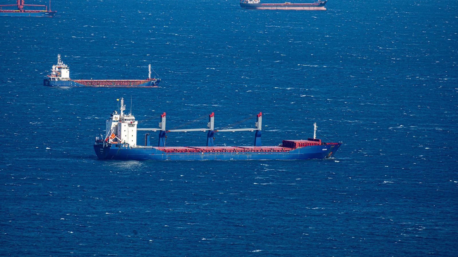 Aerial view of multiple cargo ships navigating through the vast blue ocean, capturing maritime commerce.