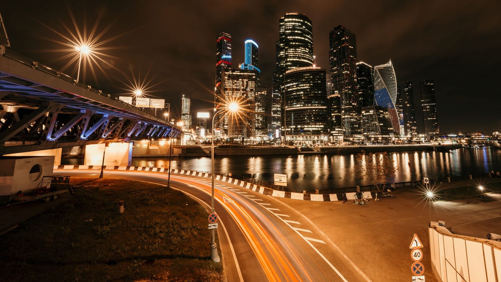 Stunning nighttime cityscape featuring illuminated skyscrapers and a bridge with glowing streetlights.