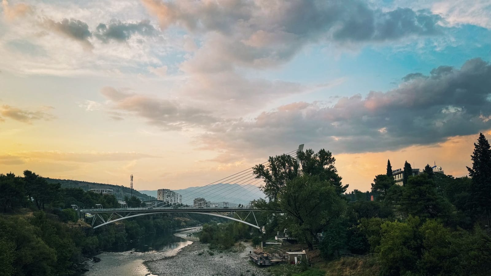 Beautiful sunset over Millennium Bridge in Montenegro with lush greenery and river.
